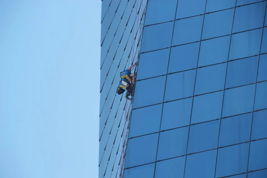 Une personne en équipement de protection désinfecte un bureau de bureau à l’aide d’un appareil de fumigation en plein jour.